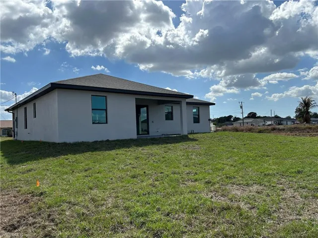Back of property featuring stucco siding, a yard, and a patio