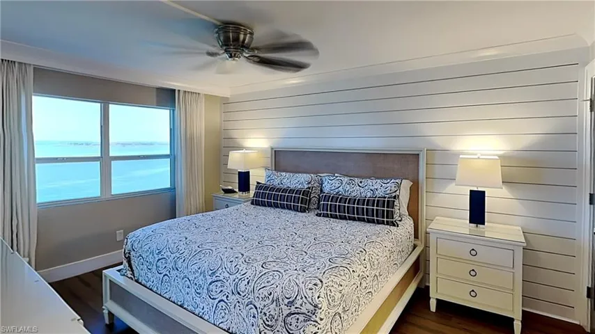 Bedroom featuring expansive windows, wood-finish flooring, a ceiling fan, and a shiplap accent wall
