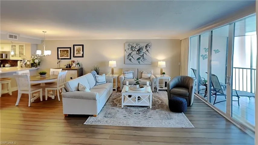 Expansive living area with wood-finish flooring, featuring a dedicated dining space with chandelier lighting