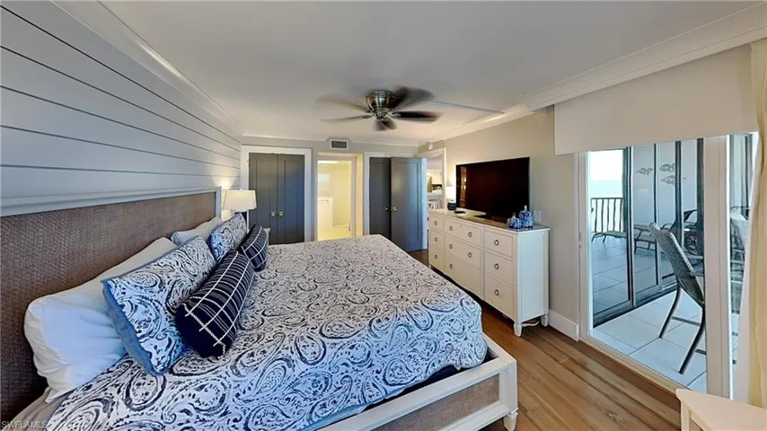 Bedroom featuring wood-finish flooring, a ceiling fan, and a shiplap accent wall