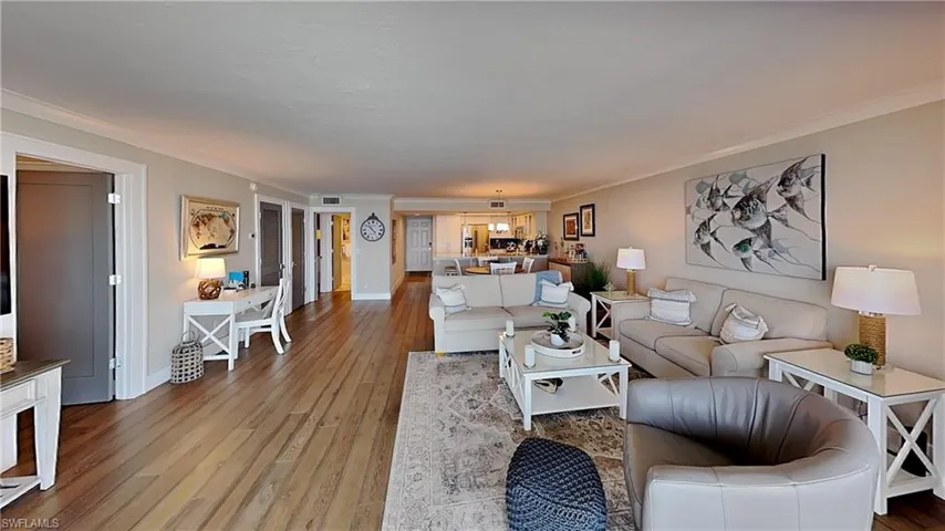 Spacious living area featuring wood-finish flooring, light-toned walls, and crown molding