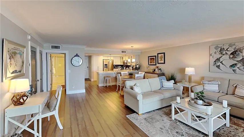 Open-concept living area featuring wood-finish flooring and crown molding