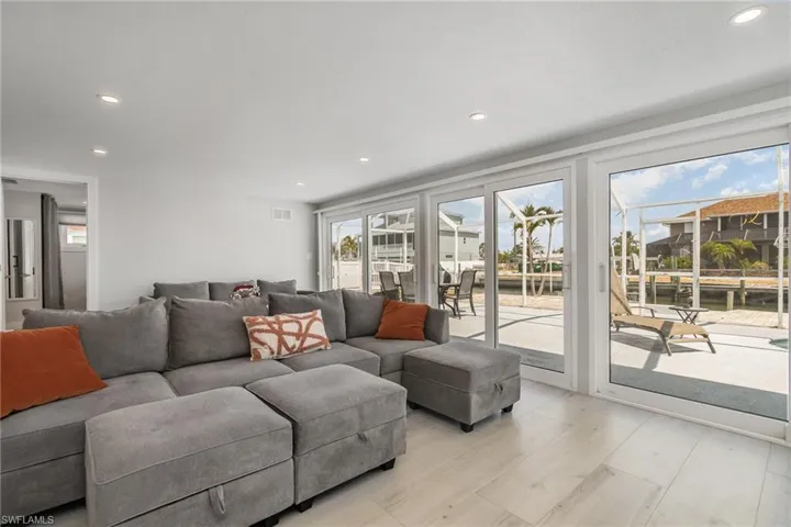 Living room featuring healthy amount of natural light,  large sliders to screened in pool area, light wood grain tile floors , and recessed lighting