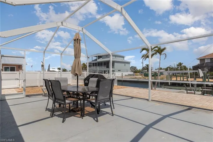 View of patio, outdoor dining area, fence, and a water view