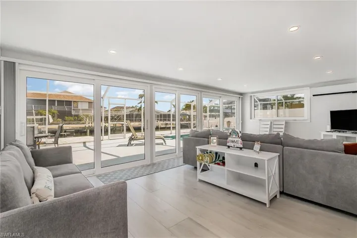 Living room featuring healthy amount of natural light,  large sliders to screened in pool area, light wood grain tile floors , and recessed lighting