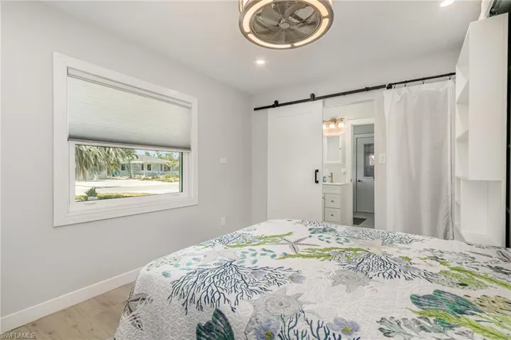Bedroom with light wood grain tile floors, a barn door, recessed lighting, and featuring a Murphy Bed for extra