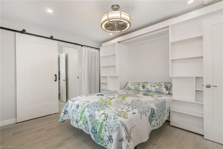 Bedroom with light wood grain tile floors, a barn door, recessed lighting and ceiling fan , and featuring a Murphy Bed for extra floor space,