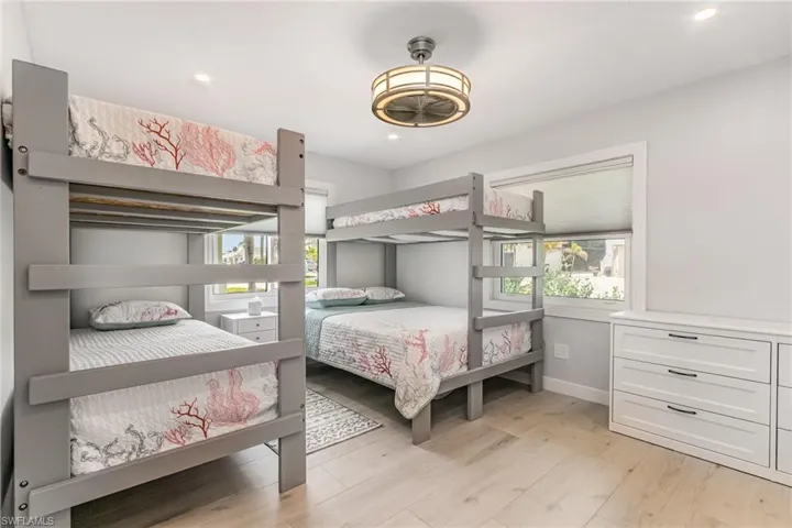 Bedroom with light wood grain tile floors, recessed lighting & ceiling fan