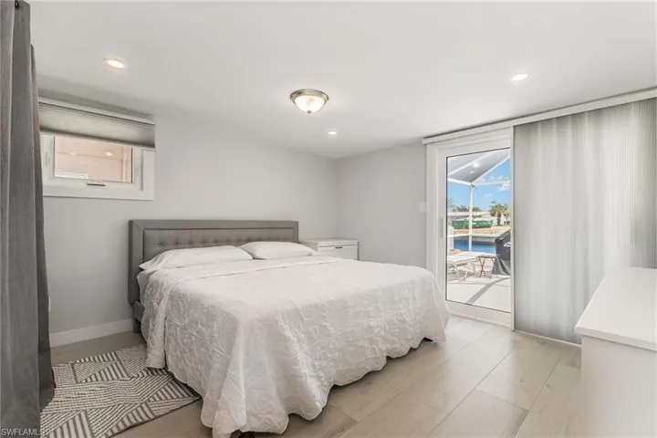 Primary Bedroom with light wood grain tile floors, a barn door, recessed lighting, baseboards, and ensuite bath and slider to back screened in  patio