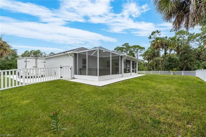Rear view of property featuring a lanai and a lawn