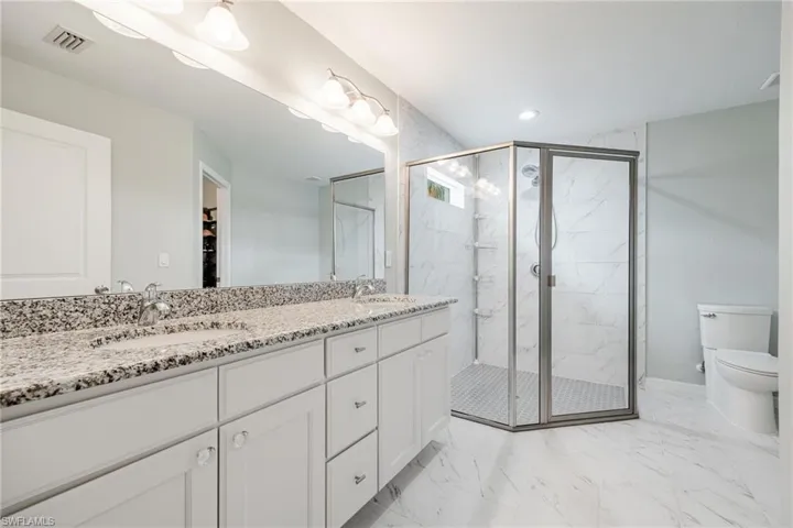 Bathroom featuring tile patterned floors, vanity, walk in shower, and toilet