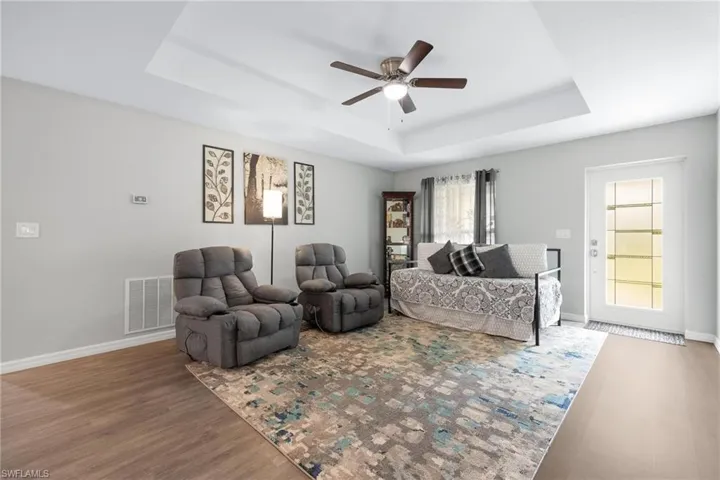 Living room featuring a tray ceiling, ceiling fan, and hardwood / wood-style floors