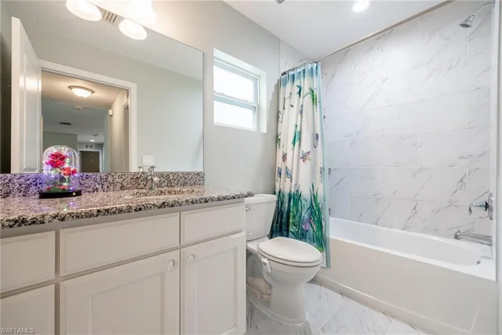Full bathroom with tile patterned flooring, toilet, vanity, and shower / bath combo with shower curtain