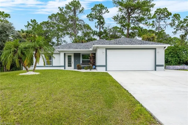 Single story home with a garage and a front lawn