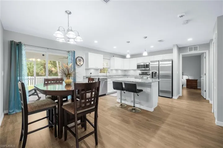 Dining area with sink, an inviting chandelier, and light wood-type flooring