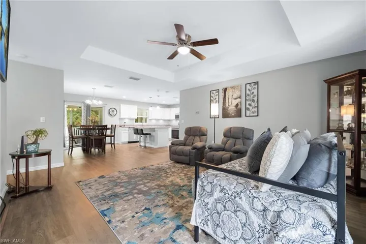 Living room featuring ceiling fan with notable chandelier, hardwood / wood-style flooring, and a tray ceiling