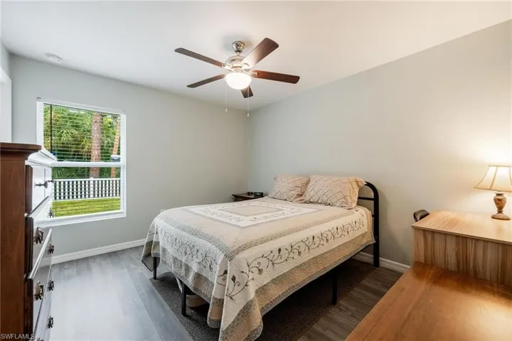 Bedroom with ceiling fan, dark wood-type flooring, and multiple windows
