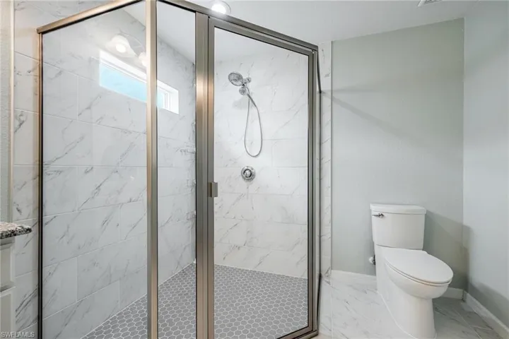 Bathroom featuring toilet, tile patterned flooring, and a shower with shower door