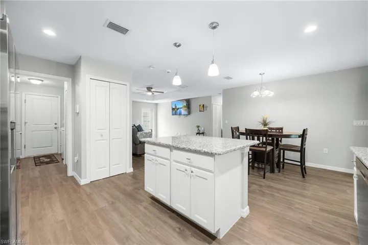 Kitchen with pendant lighting, ceiling fan with notable chandelier, light wood-type flooring, and white cabinetry