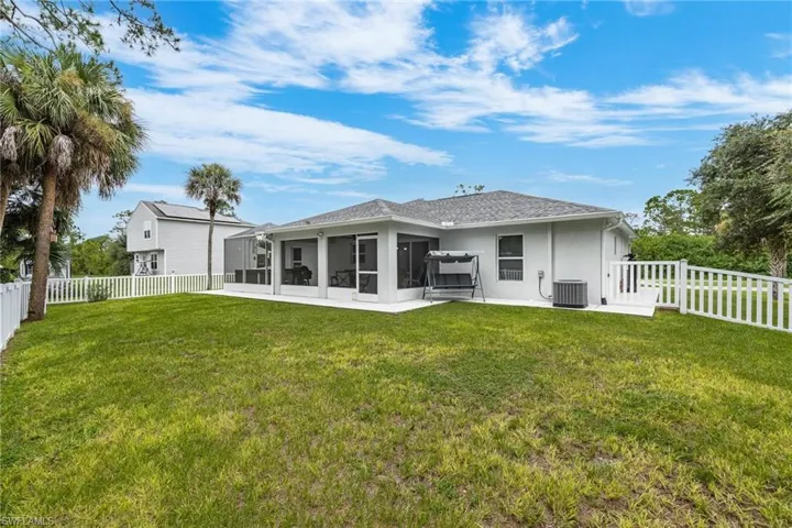 Rear view of property featuring a sunroom, central air condition unit, and a lawn