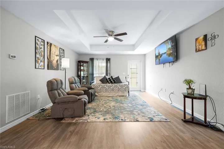 Living room with ceiling fan, hardwood / wood-style flooring, and a tray ceiling