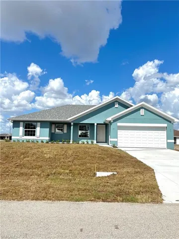 Single story home featuring driveway, a front yard, an attached garage, and roof with shingles