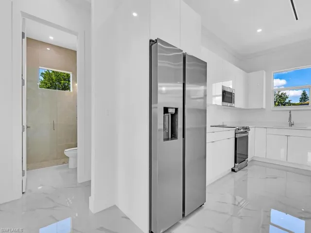 Kitchen featuring a wealth of natural light, white cabinets, sink, and stainless steel appliances
