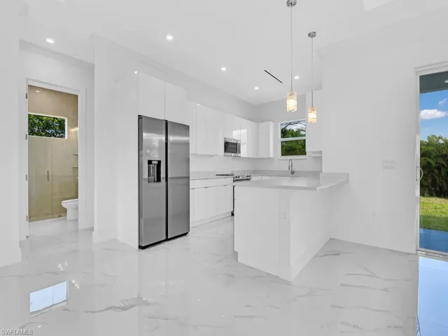 Kitchen featuring white cabinetry, appliances with stainless steel finishes, pendant lighting, sink, and kitchen peninsula