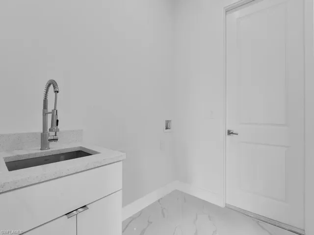 Clothes washing area featuring hookup for a washing machine, cabinets, and sink