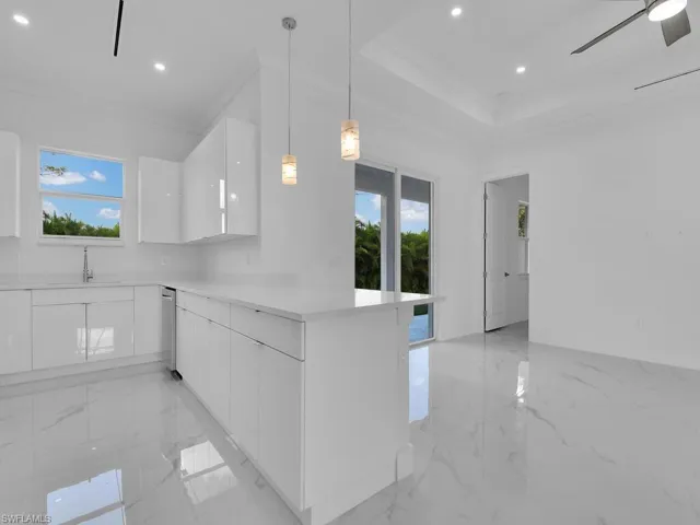 Kitchen with white cabinets, kitchen peninsula, sink, ceiling fan, and pendant lighting