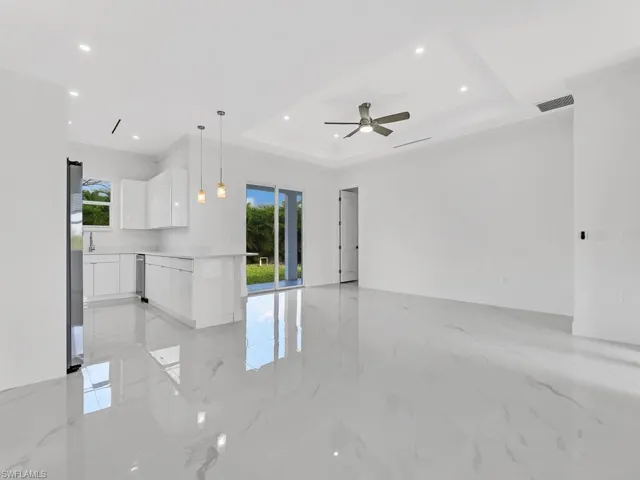 Unfurnished living room featuring a tray ceiling and ceiling fan