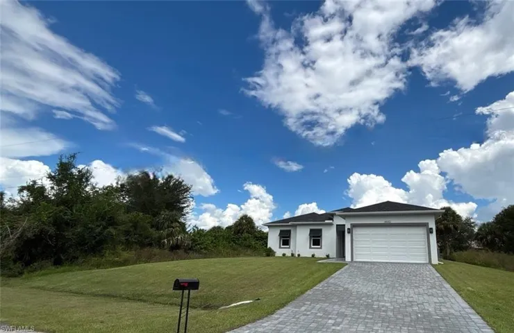 Single story home featuring a front yard, stucco siding, an attached garage, and decorative driveway