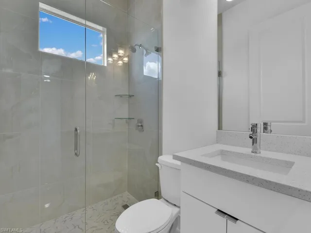 Bathroom featuring an enclosed shower, vanity, and toilet