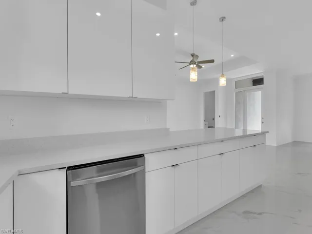 Kitchen featuring white cabinetry, pendant lighting, stainless steel dishwasher, and ceiling fan