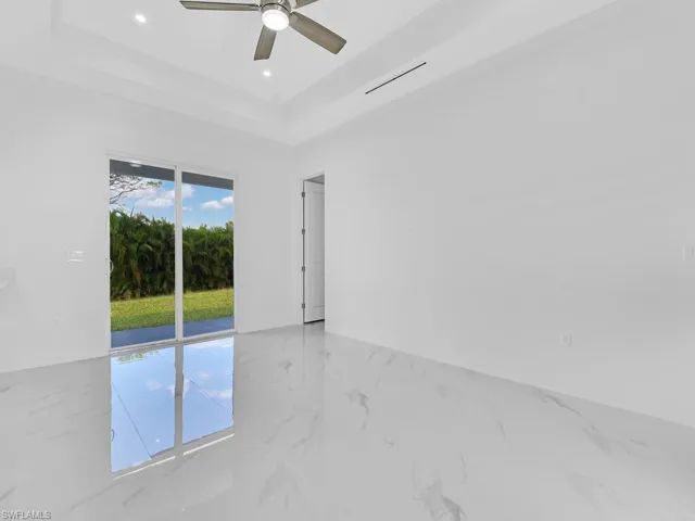 Unfurnished room featuring ceiling fan and a tray ceiling