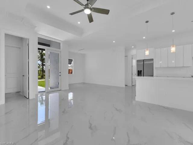 Unfurnished living room with crown molding, ceiling fan, and a raised ceiling