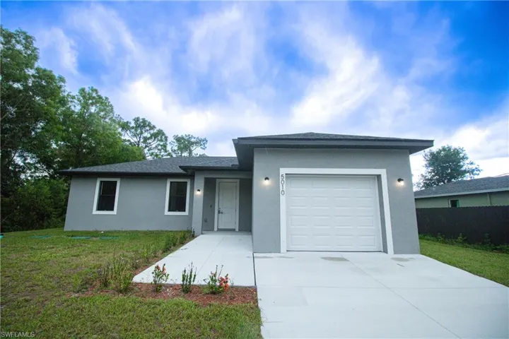 View of front of house featuring a garage, stucco siding, a front yard, and concrete driveway