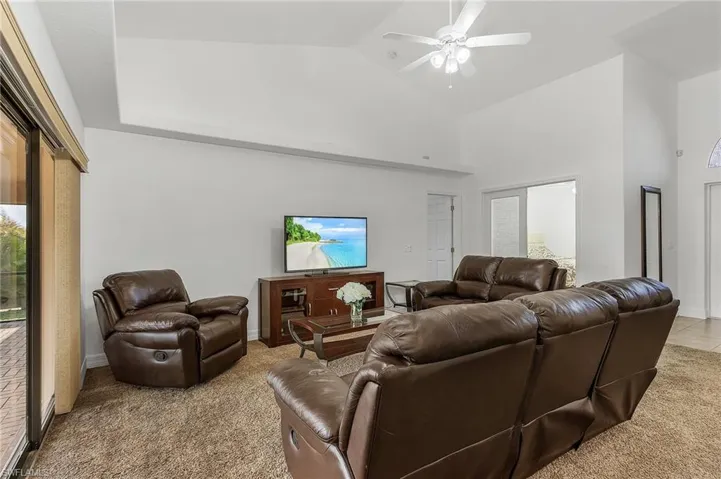 Carpeted living room featuring high vaulted ceiling and ceiling fan