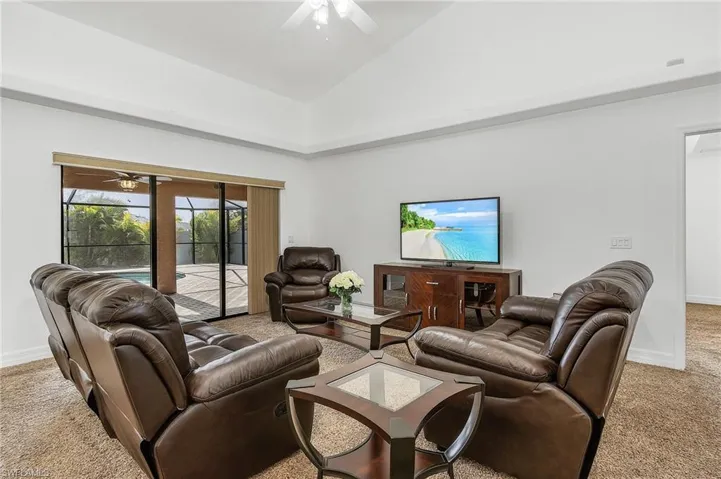 Living room with light carpet, high vaulted ceiling, and ceiling fan