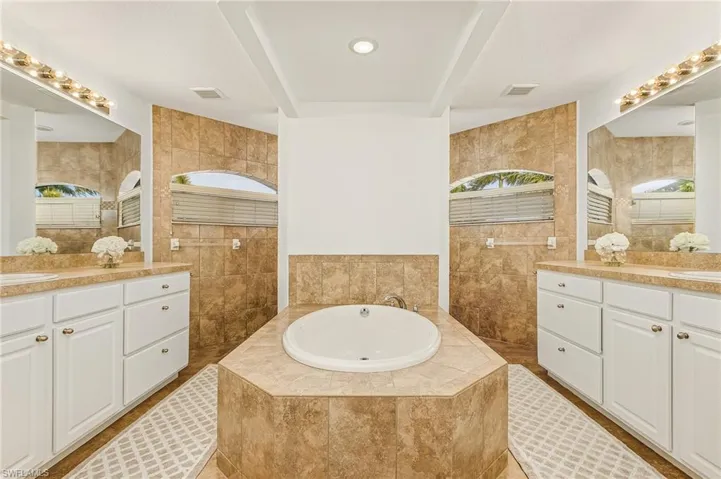 Bathroom with vanity, tile walls, and tiled tub