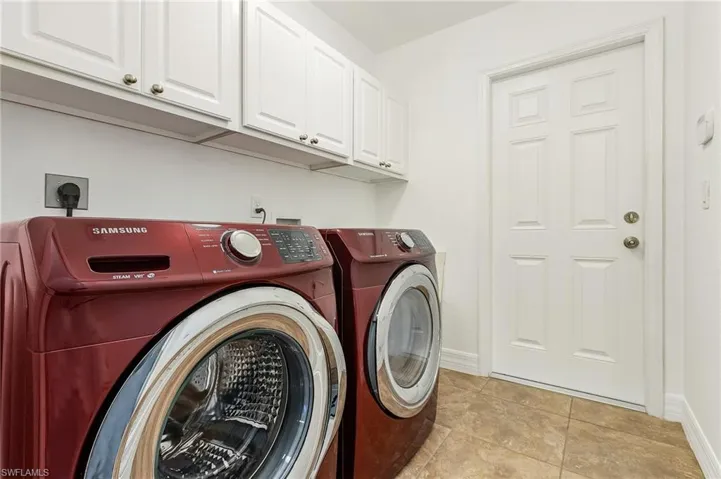 Washroom featuring light tile patterned floors, cabinets, and washer and clothes dryer