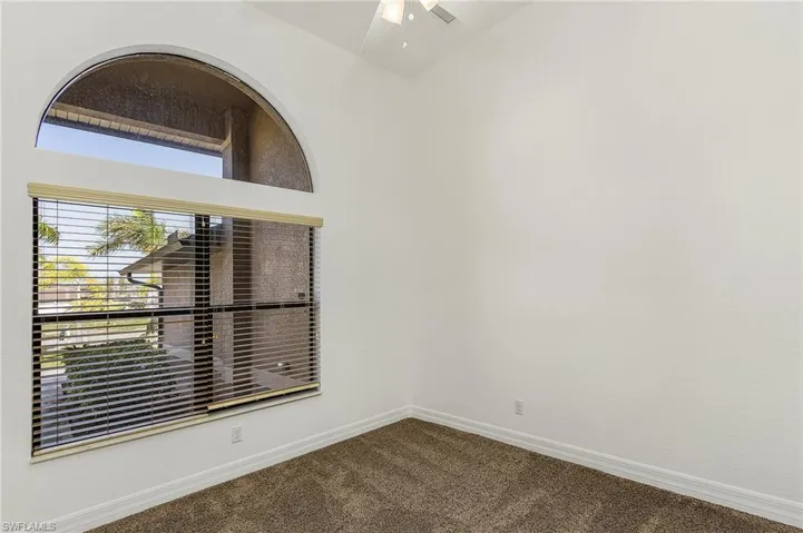 Empty room with carpet floors, ceiling fan, and vaulted ceiling
