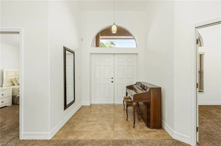 Carpeted foyer featuring a high ceiling