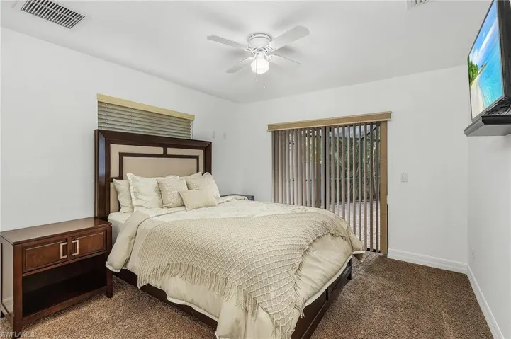 Carpeted bedroom featuring multiple windows and ceiling fan