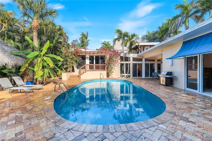 Outdoor pool with a patio area, grilling area, a sunroom, and stairs