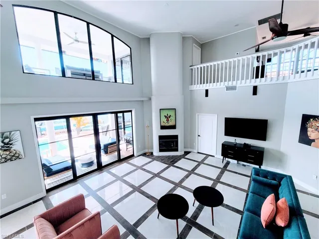 Tiled living room with a high ceiling, ceiling fan, and a large fireplace