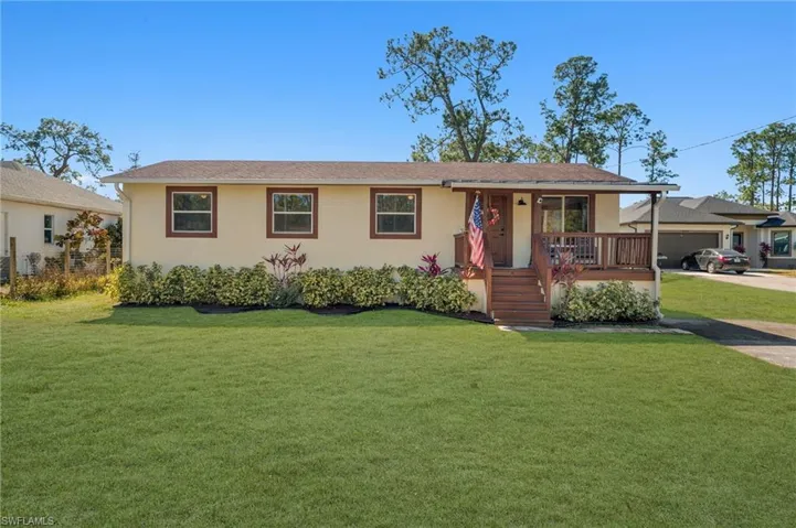 Single story home with a front yard, covered porch, and stucco siding