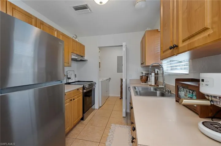 Kitchen featuring stainless steel appliances, light countertops, light tile patterned floors, separate washer and dryer