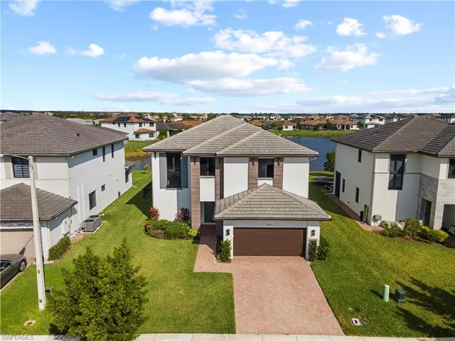 View of front of home featuring a tile roof, stucco siding, a yard, and decorative driveway