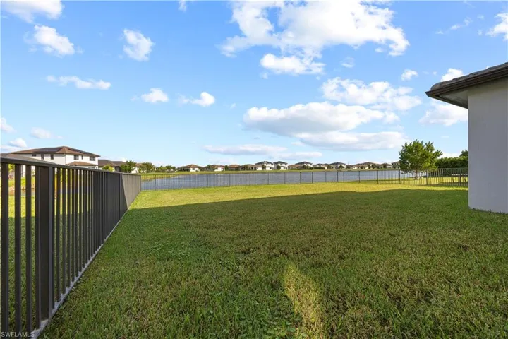 Large backyard space with fence and lake view.